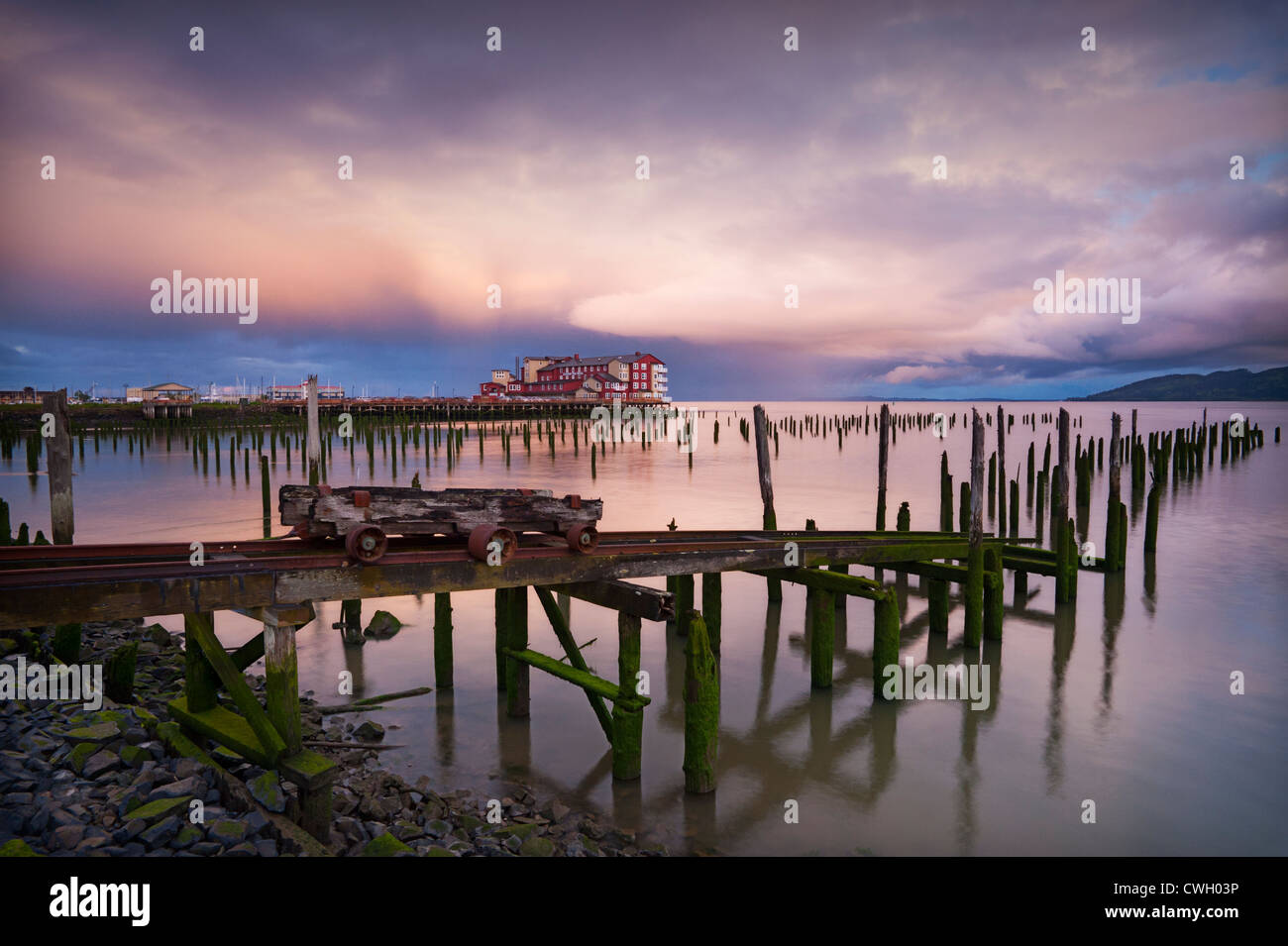 Nuages spectaculaires et le lever du soleil la lumière reflétée dans le fleuve Columbia avec cent ans, des pilotis et le Cannery Pier Hotel, Astoria, Oregon, USA Banque D'Images