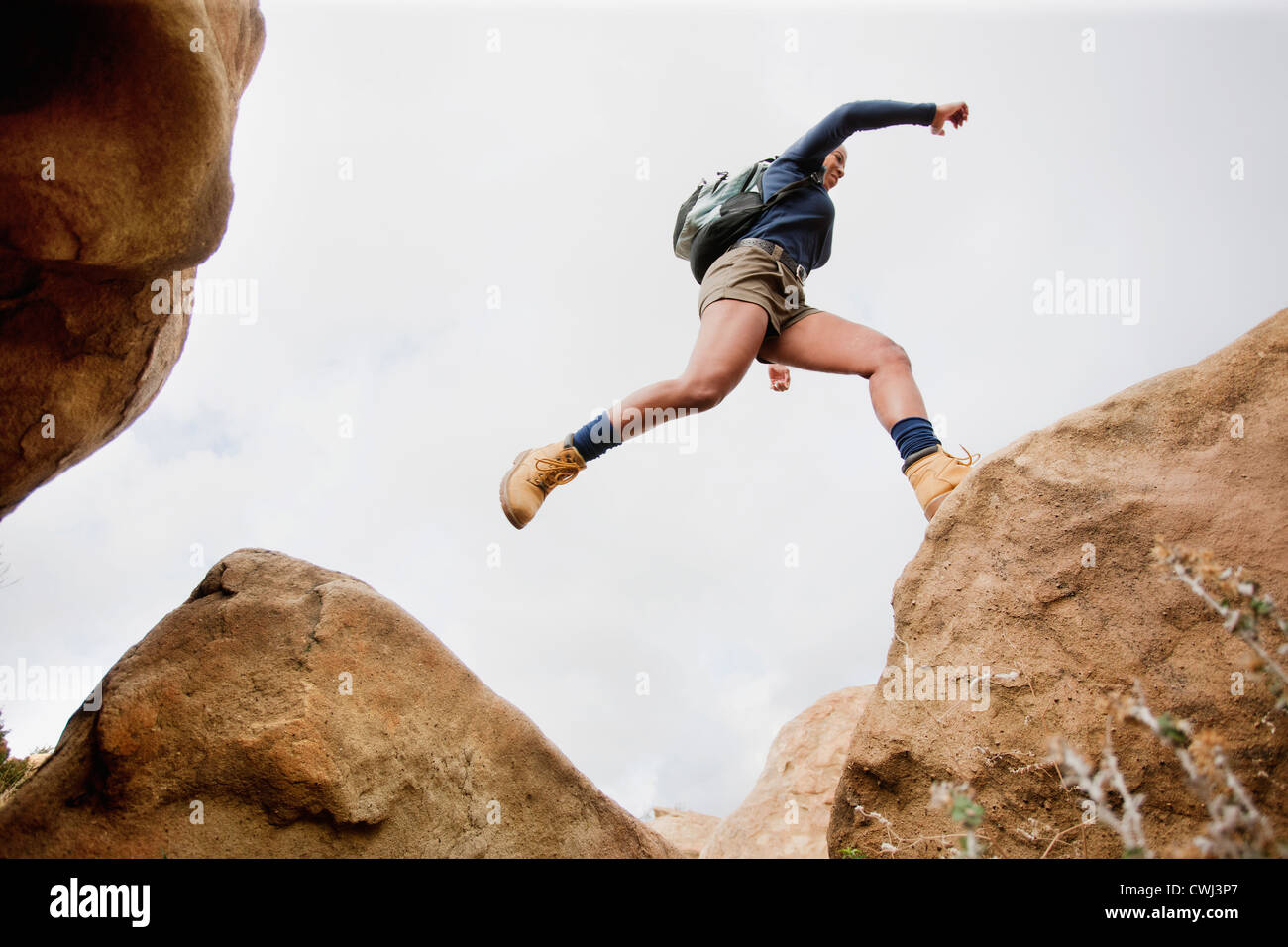 Black woman jumping à travers les rochers Banque D'Images
