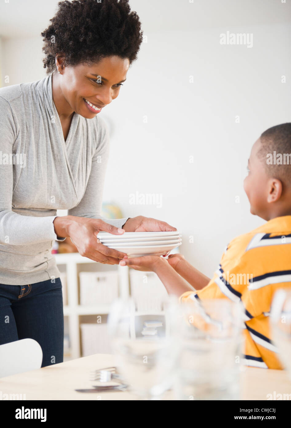 Fils noir mère aidant à mettre la table Banque D'Images