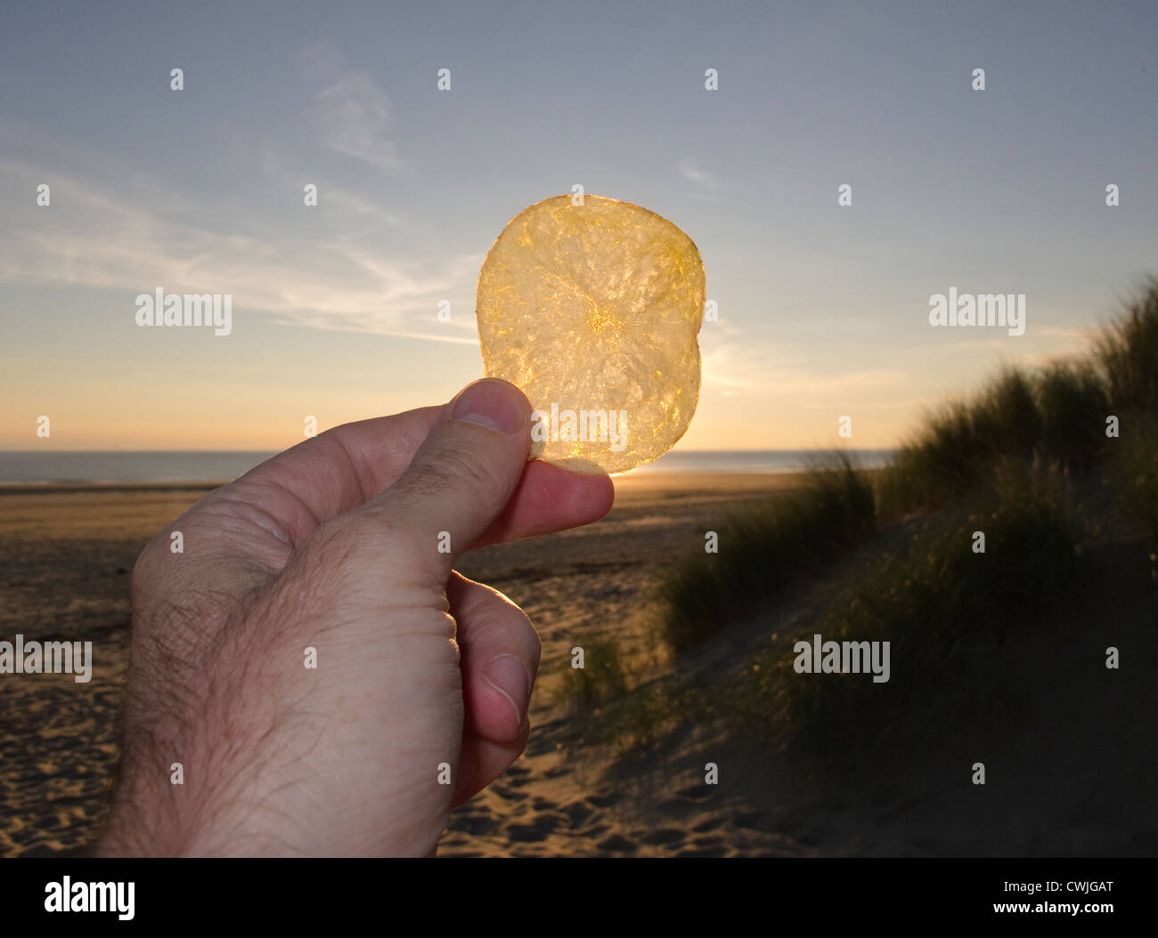 Une pomme de terre crisp aider jusqu'à l'encontre de la coucher de soleil sur une plage Banque D'Images