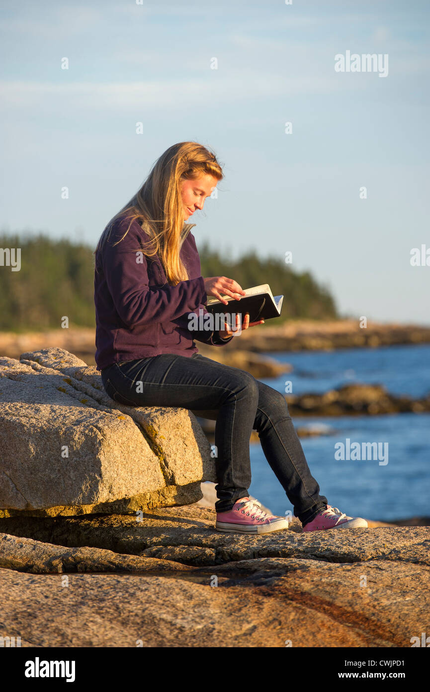 Jeune femme avec journal au coucher du soleil, la péninsule de Schoodic, Maine, USA Banque D'Images