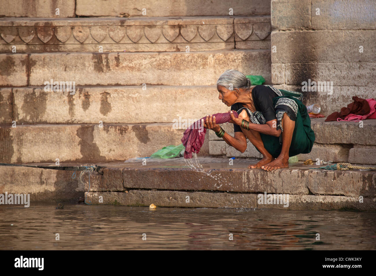 Vieille lavandière lave-linge dans l'eau polluée du Gange à Varanasi, Uttar Pradesh, Inde Banque D'Images