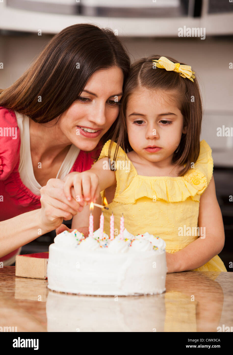 Caucasian mother and daughter lighting birthday candles Banque D'Images