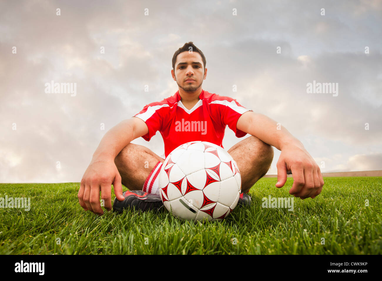 Hispanic soccer player sitting with ball Banque D'Images