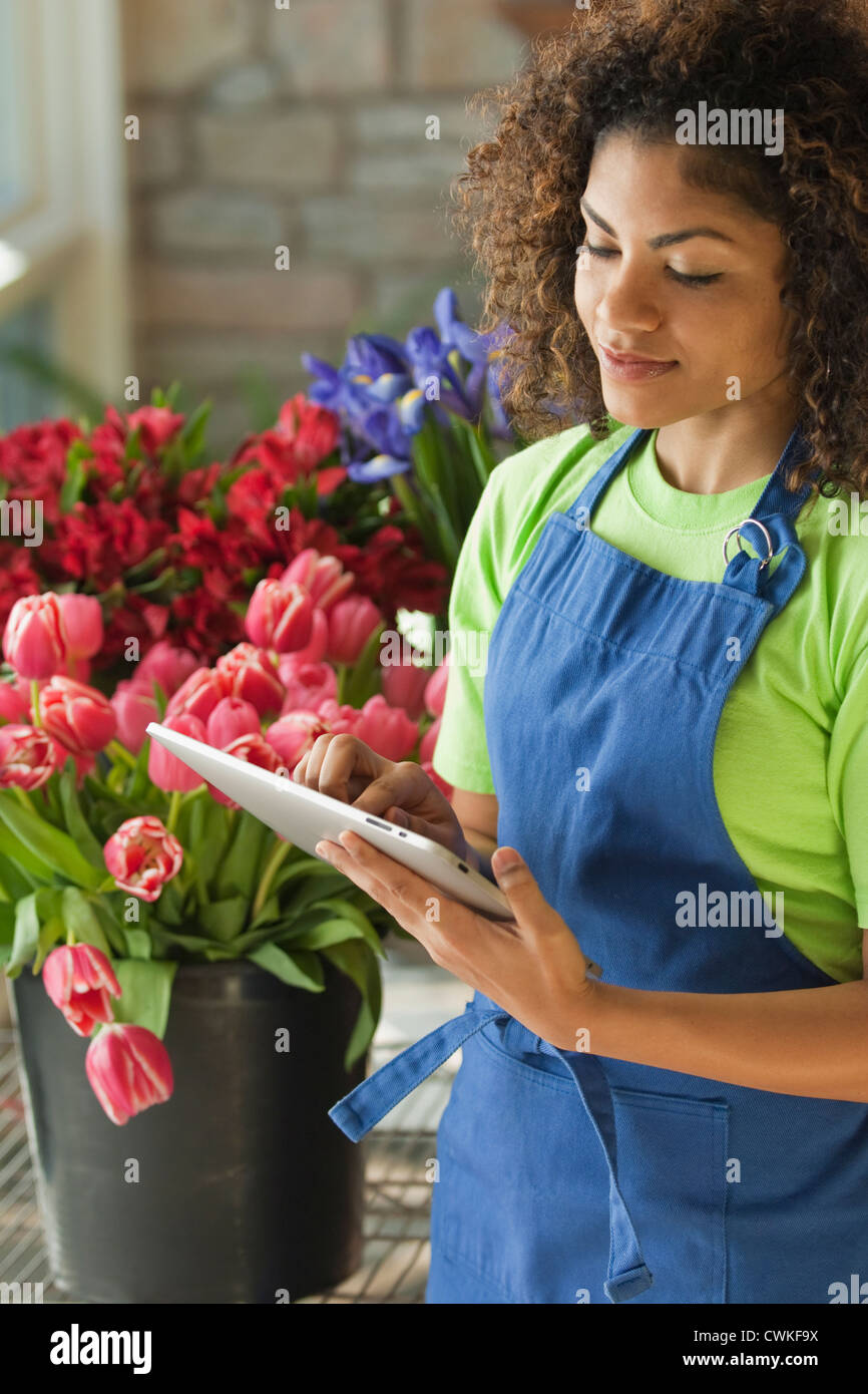 Mixed Race florist using digital tablet Banque D'Images