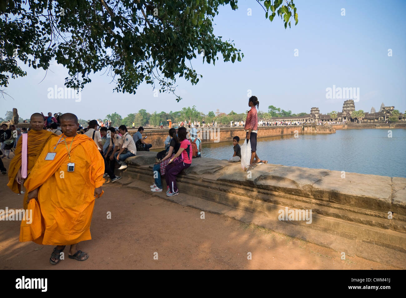 Vue horizontale de touristes par séance et marcher le long de la chaussée principale à l'ouest de l'entrée dans le Gopuram, Angkor Wat. Banque D'Images