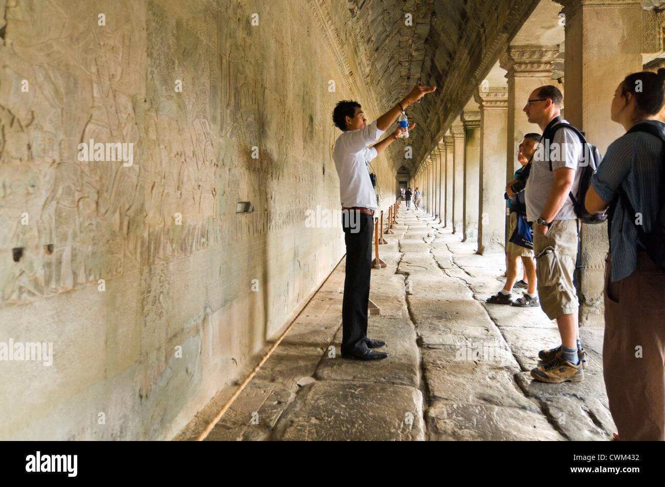 Vue horizontale d'un guide et d'un groupe de touristes debout devant l'étonnant au Prasat Angkor Wat sculptures Banque D'Images