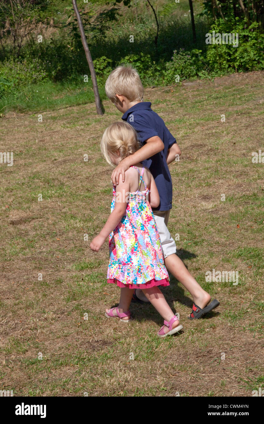 Frère et soeur de l'âge de 8 et 4 de marcher à travers la maison d'été de la cour avant. Zawady Centre de la Pologne Banque D'Images