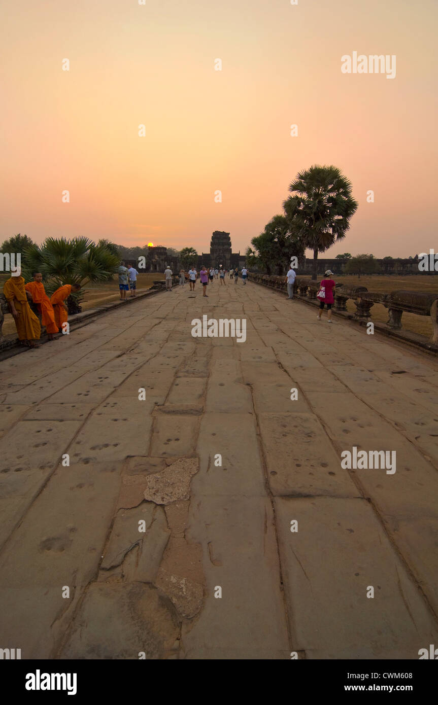 Vue verticale de moines assis le long de la chaussée de Naga à Angkor Wat à Siem Reap au coucher du soleil. Banque D'Images