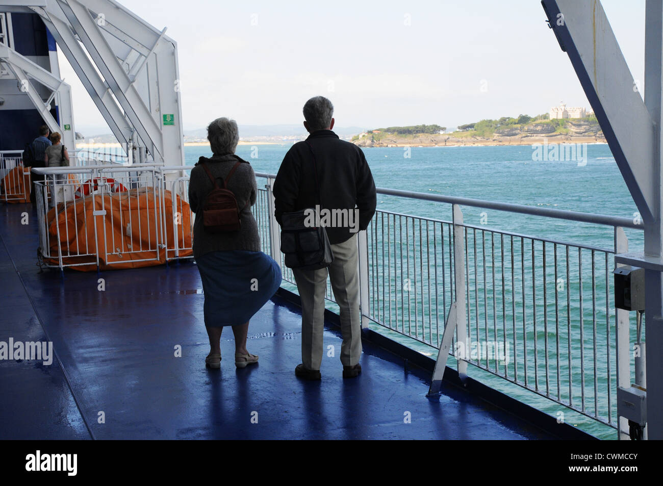 Vue arrière du couple de personnes âgées sur le pont en direction de la terre, à bord de ferries de croisière, à l'entrée de Santander, Espagne. Banque D'Images