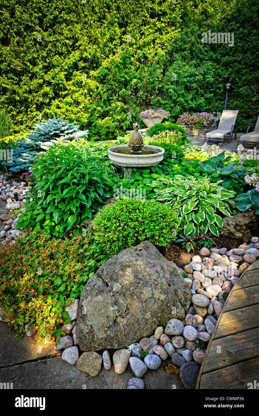 Vivaces luxuriant jardin avec fontaine Plantes et arbres Banque D'Images