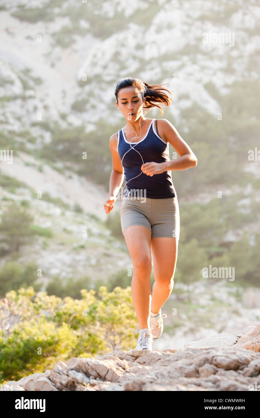 France, Marseille, young woman jogging sur terrain rocailleux Banque D'Images