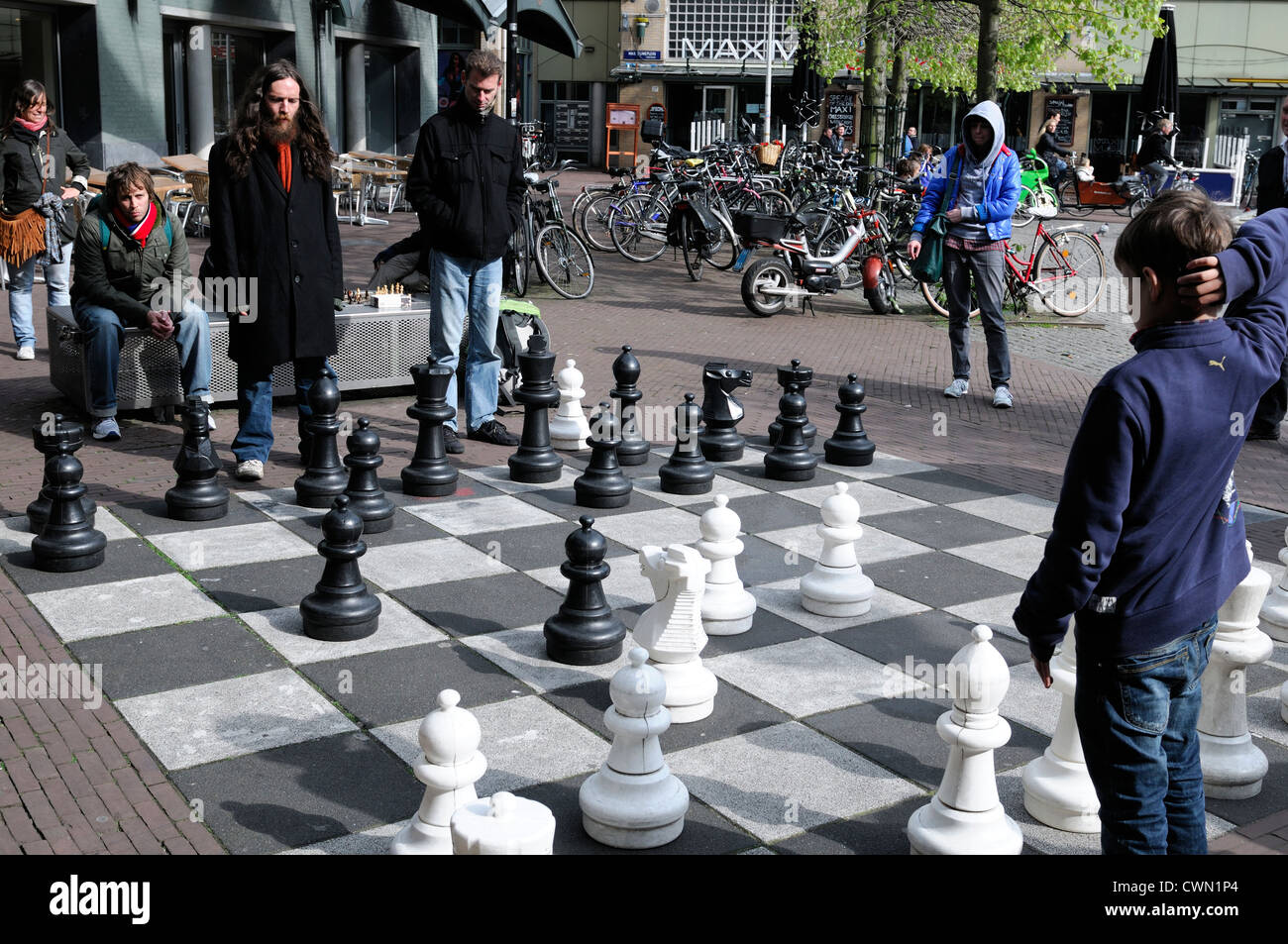 Garçon jouer jouer aux échecs à l'extérieur de l'homme gros morceaux paving stone street jeux jeu Amsterdam Pays-Bas Loisirs Loisirs Banque D'Images