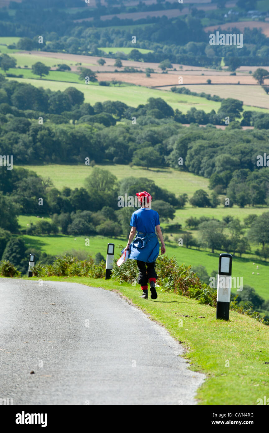 Une femme marchant le long de la route en haut de la longue Mynd, Shropshire Banque D'Images