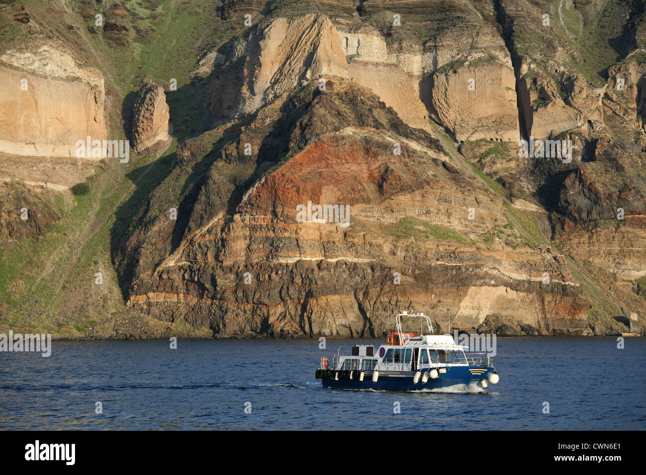 Un petit navire à voiles de la restauration des touristes le long de la côte volcanique à Santorin, Grèce. Banque D'Images
