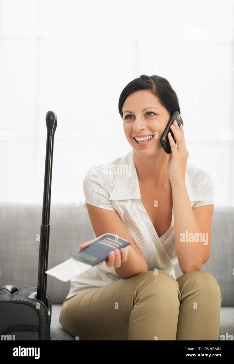 Souriante jeune femme avec passeport et billet d'air mobile parlant Banque D'Images