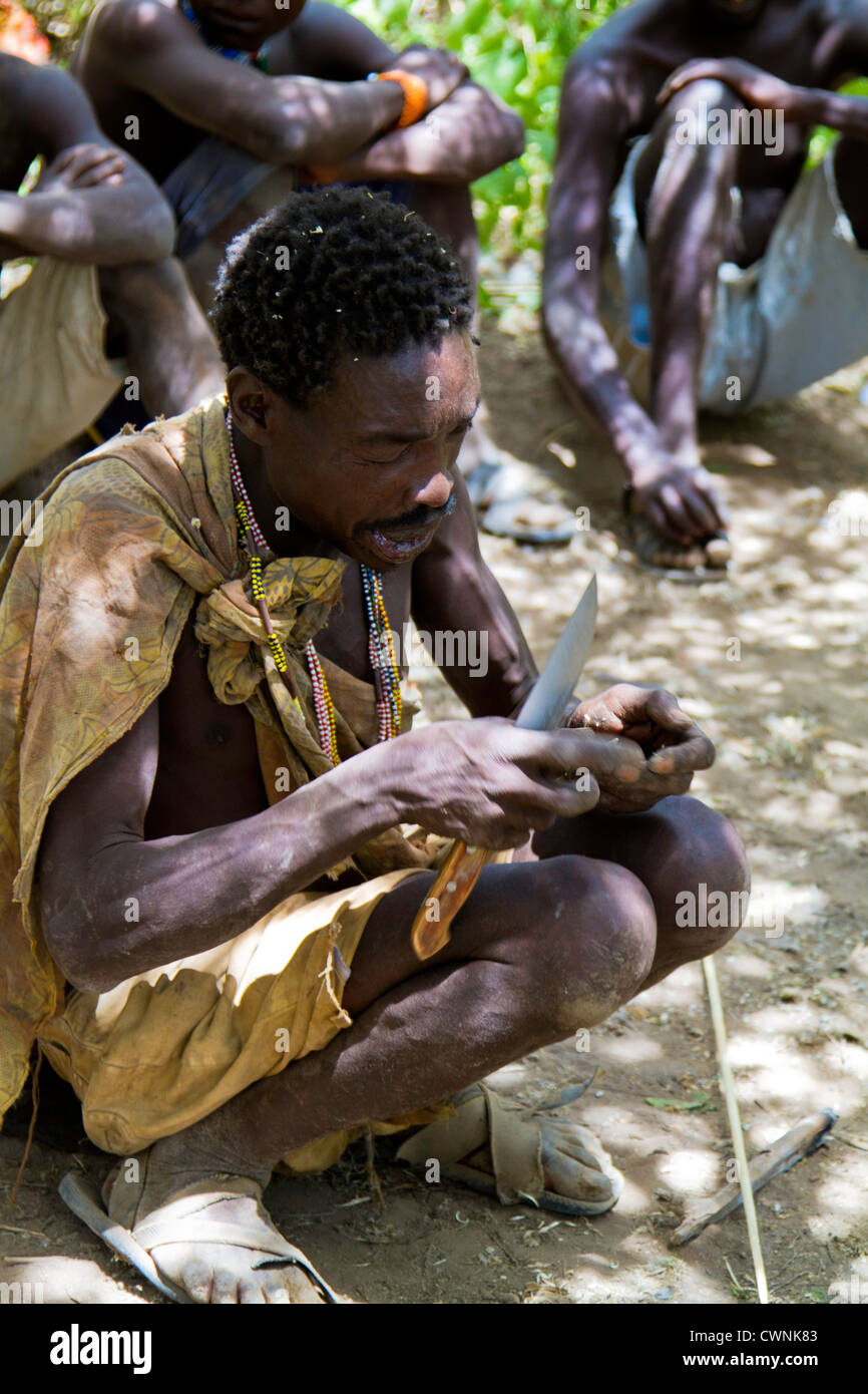 Hadza, ou Hadzabe, un groupe ethnique dans le centre-nord de la Tanzanie, vivant autour du lac Eyasi. Cet homme se taille une lance pour la chasse Banque D'Images