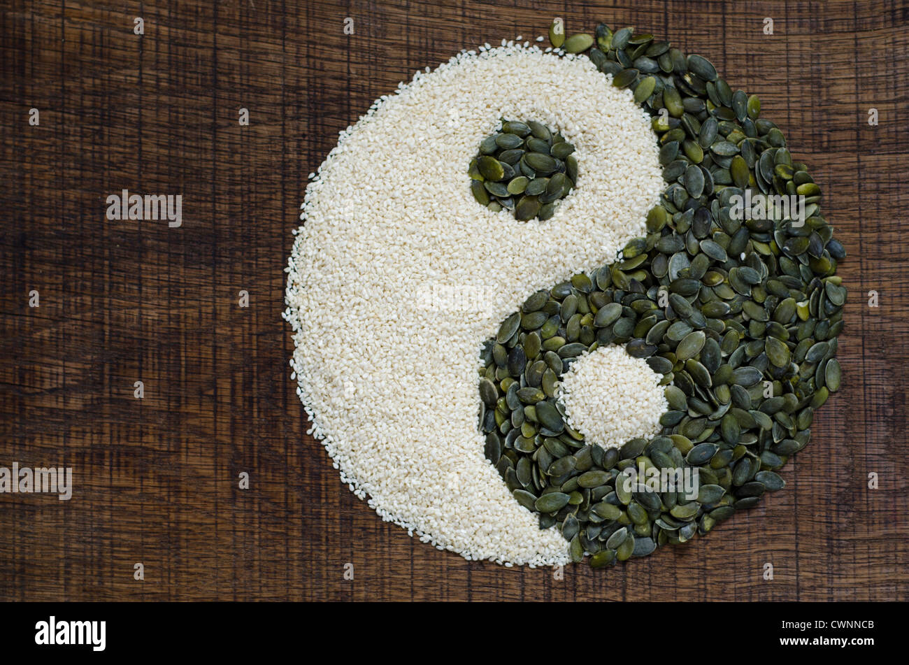 Le Yin Yang créé à partir de graines de citrouille et graines de sésame sur une surface en bois sombre. Banque D'Images