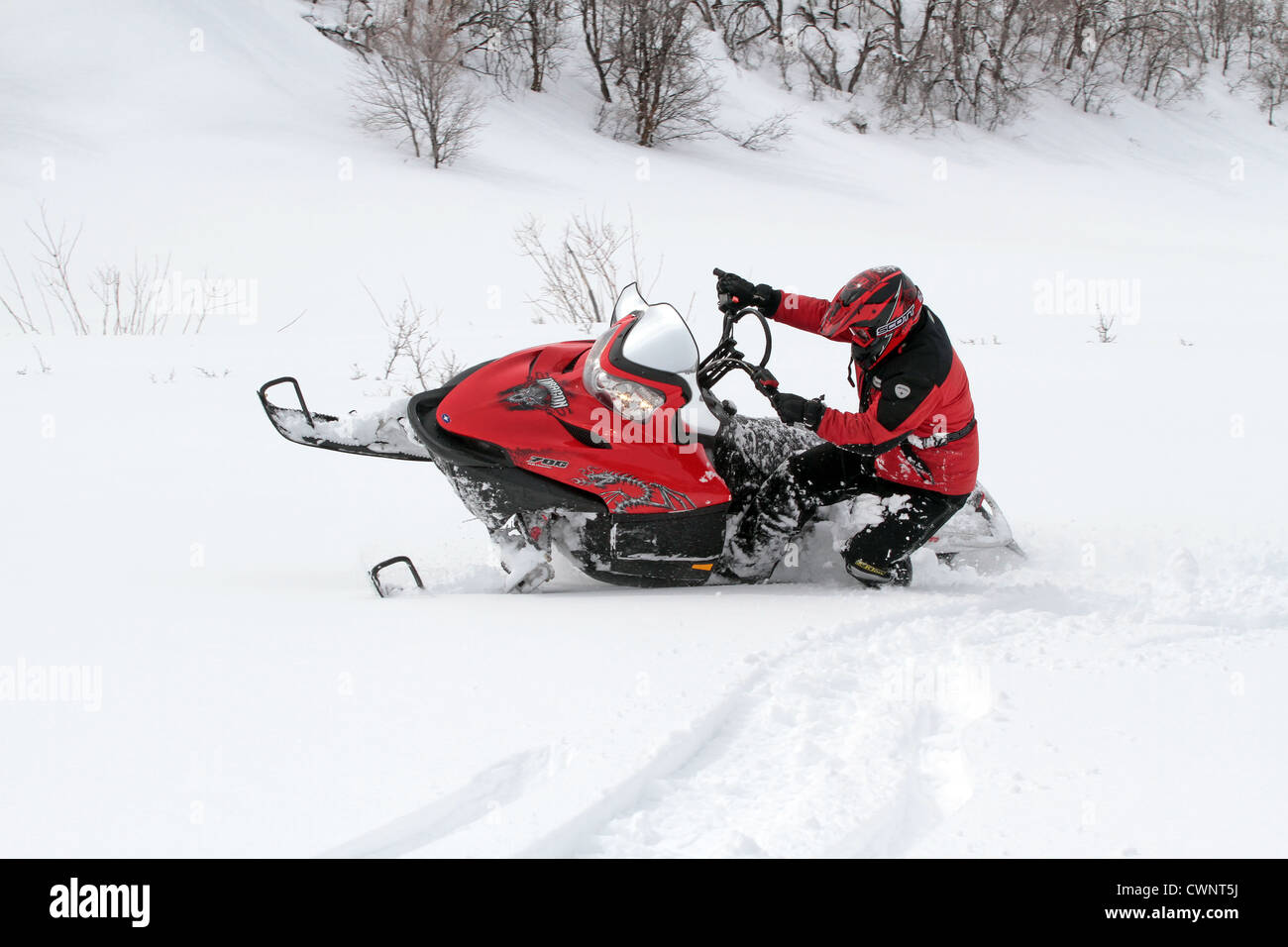 Cavalier motoneige s'amusant et en tournant dans la neige fraîche et blanche. Les virages serrés dans une prairie de montagne de haute altitude. Banque D'Images