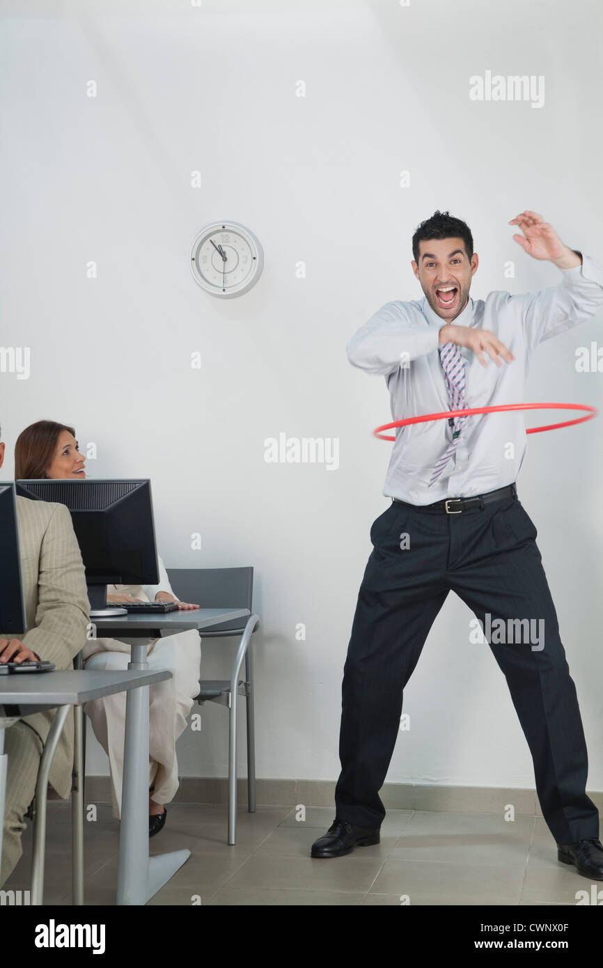 Young Woman Playing with hula hoop in office Banque D'Images