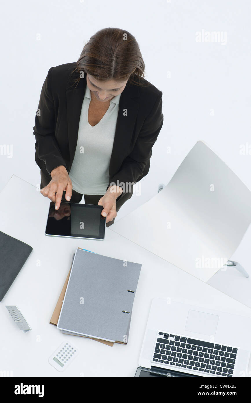 Businesswoman standing by desk using digital tablet Banque D'Images