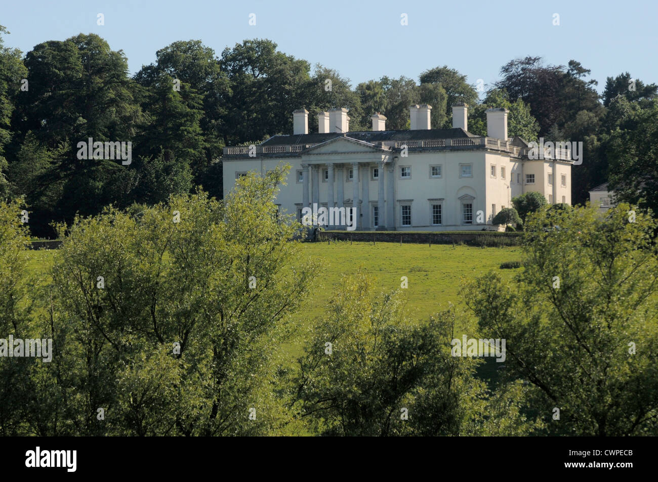 Grande demeure seigneuriale entourée d'arbres et champ avec ciel bleu Banque D'Images