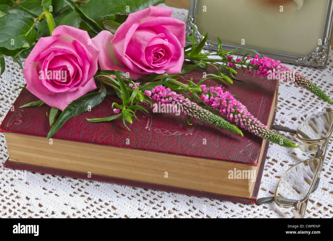 Roses rose rose et Veronica spicata, fleurs, sur un livre Banque D'Images