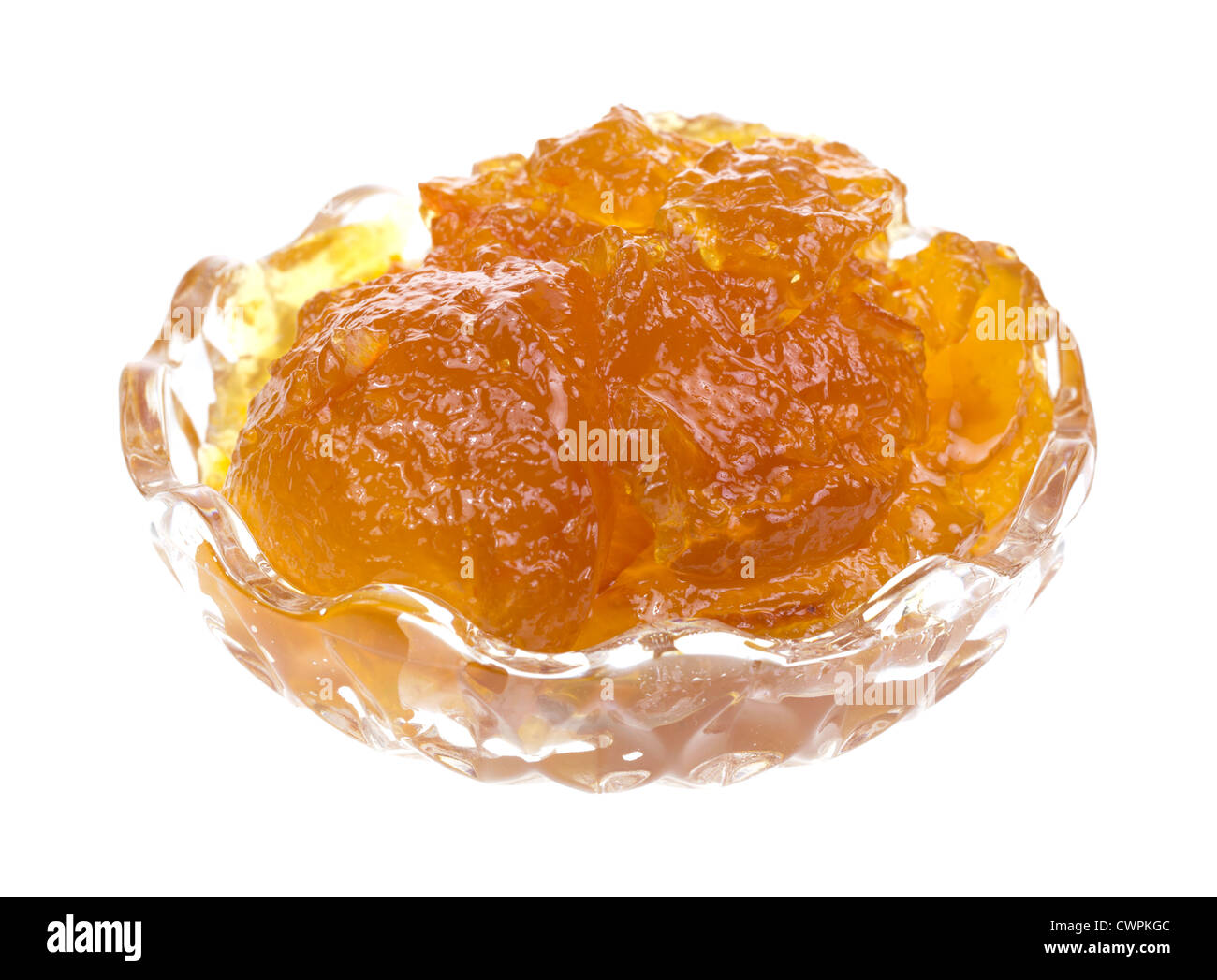 Un petit récipient en verre rempli de marmelade d'orange sur un fond blanc. Banque D'Images