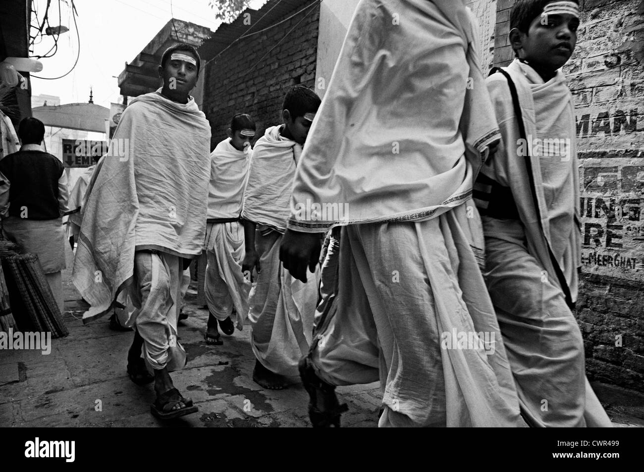 Groupe d'étudiants portant des tuniques blanches passent par une ruelle. Varanassi, Uttar Pradesh, Inde Banque D'Images