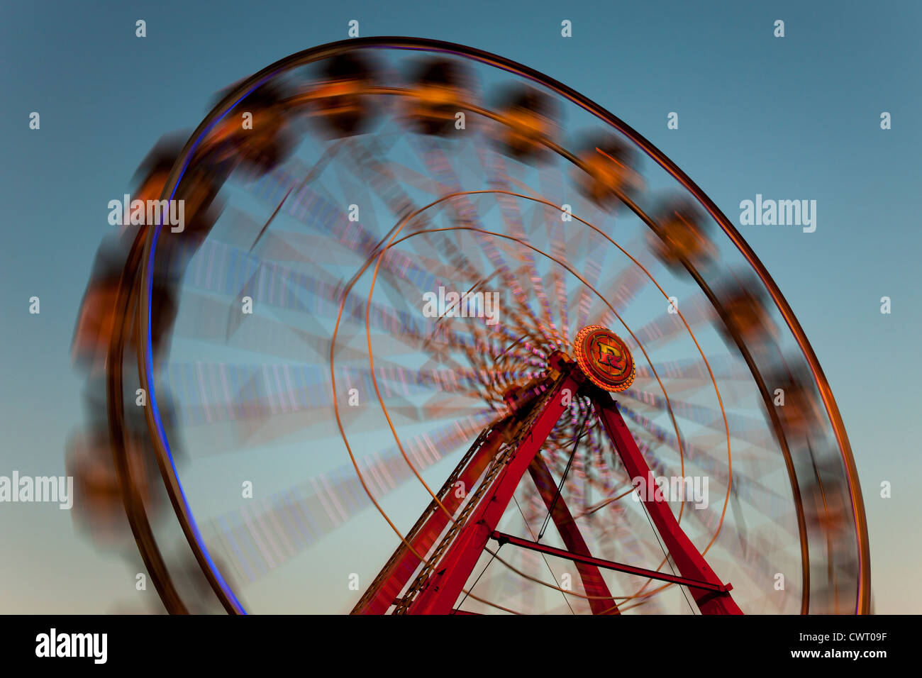 L'illuminé coloré Gentle Giant Ferris roue tourne contre le ciel crépusculaire au cours de la Foire de l'État du New Jersey. Banque D'Images
