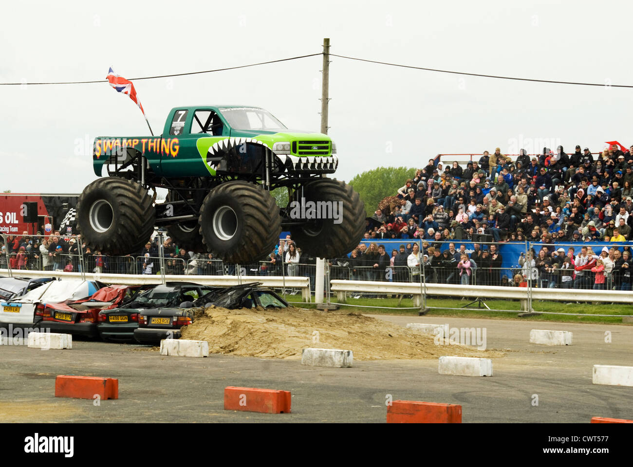 Un Monster truck nommée 'Swamp chose' à un spectacle à Santa Pod raceway sautant par-dessus une ligne de voitures. Banque D'Images