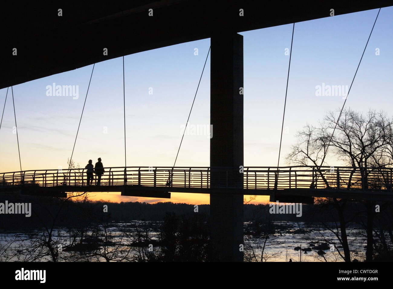 Silhouette d'un couple qui marche sur le coucher du soleil à Belle Isle pont pédestre suspendu au-dessus de la James River, Richmond, Virginie, USA Banque D'Images