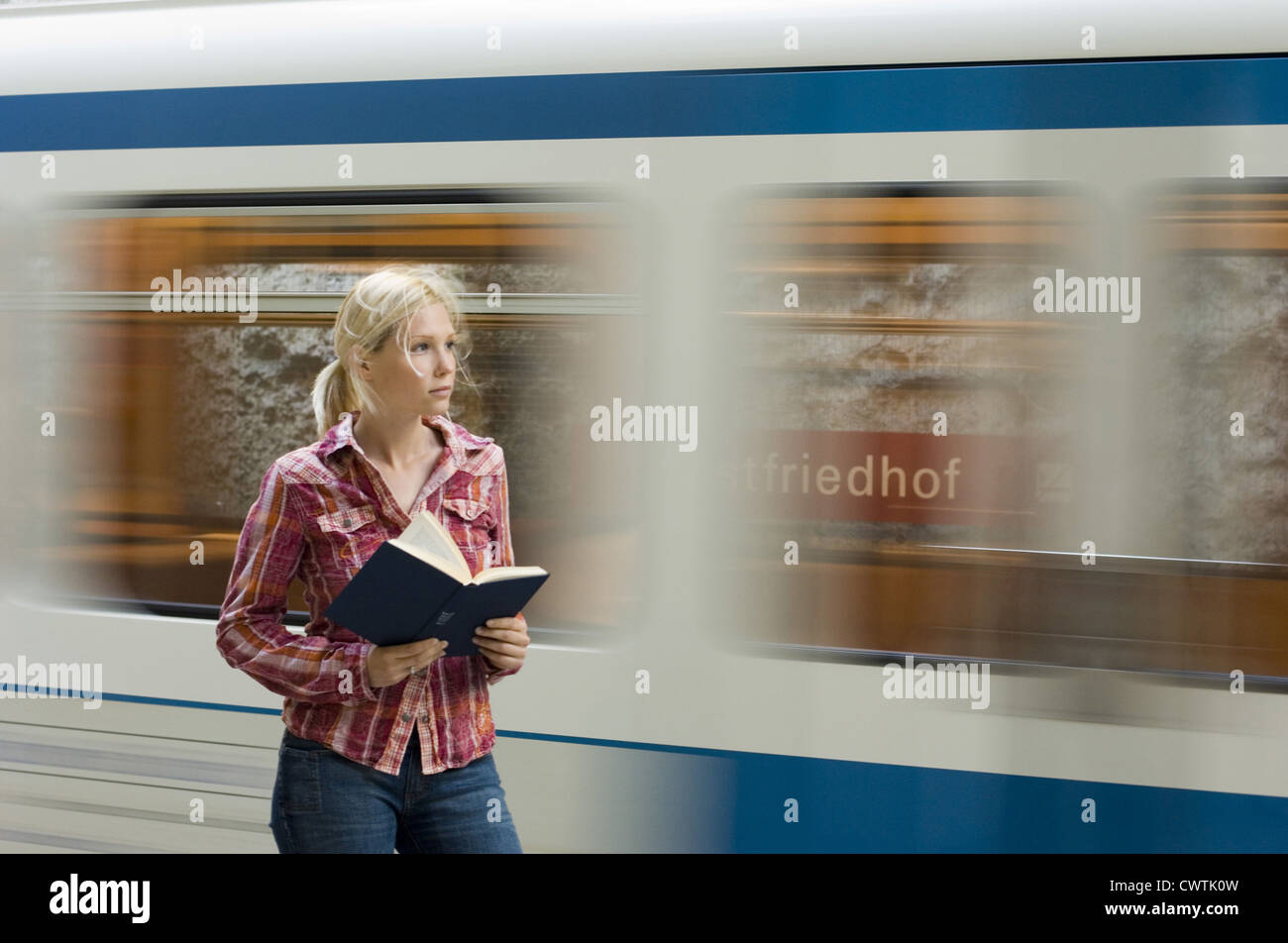 Young woman reading book in front of passant du métro Banque D'Images