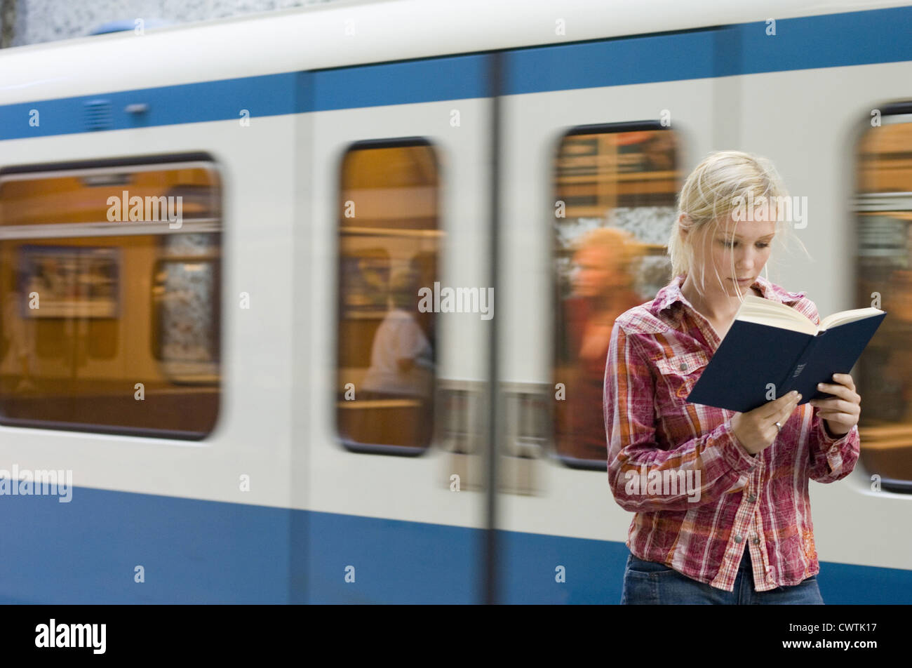 Young woman reading book in front of passant du métro Banque D'Images
