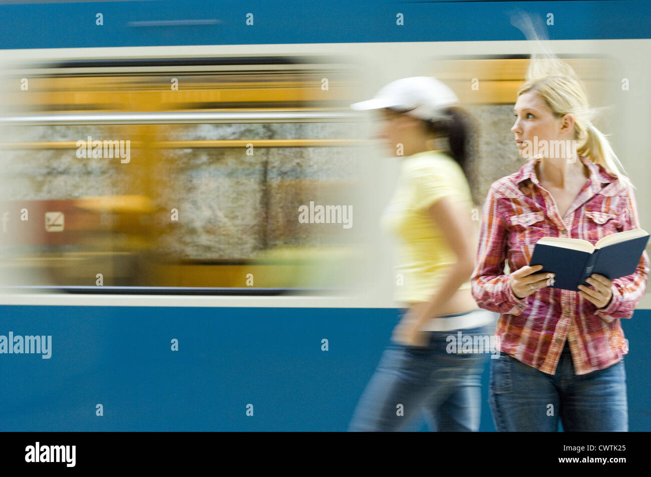 Young woman reading book in front of passant du métro Banque D'Images