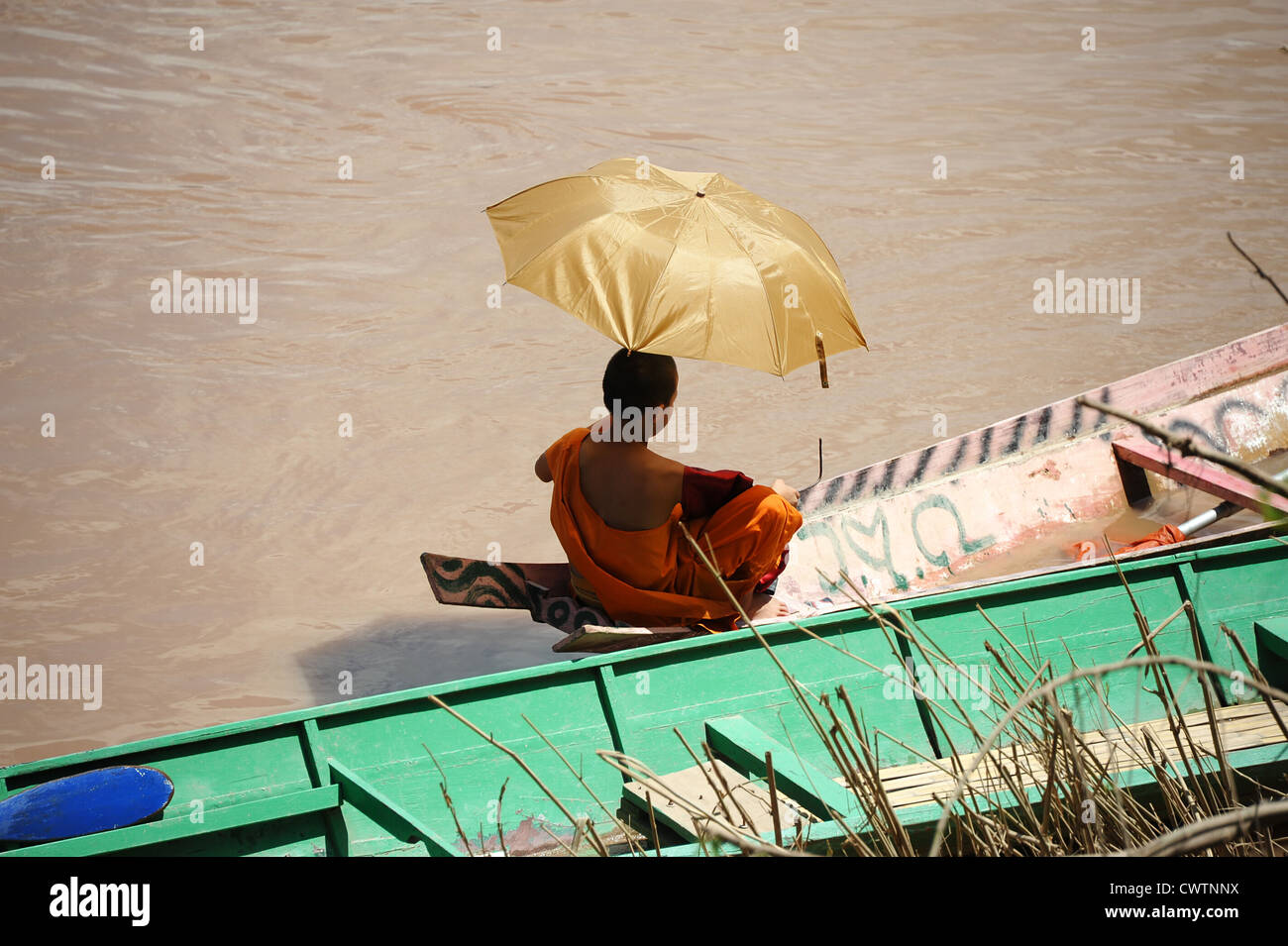 Avec parasol de moine assis en canoë sur la rivière Nam Khan à Luang Prabang, Laos Banque D'Images