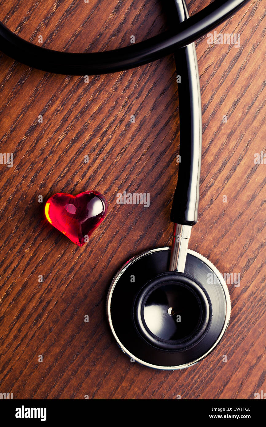 Stéthoscope et cœur rouge sur la table en bois Banque D'Images