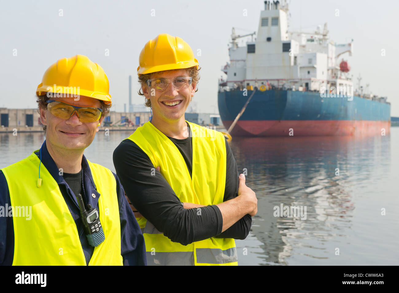 Dockers heureux et souriants posant devant un ensemble industriel pétrolier Banque D'Images