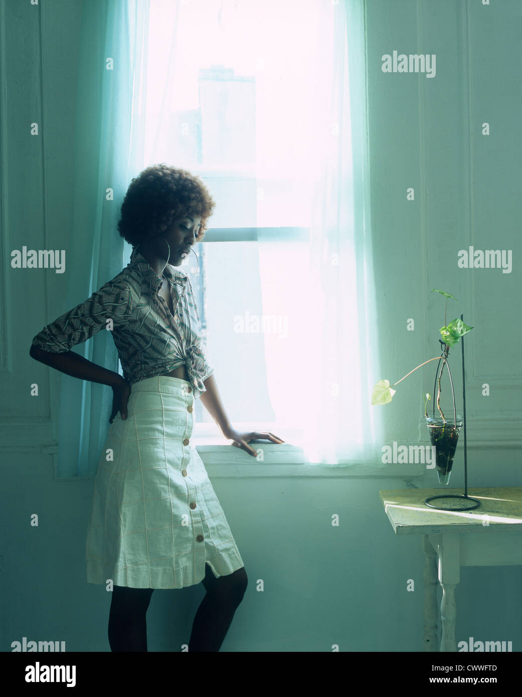 1970 Style : Noir American Woman with short rouge hued afro dans la fenêtre Banque D'Images