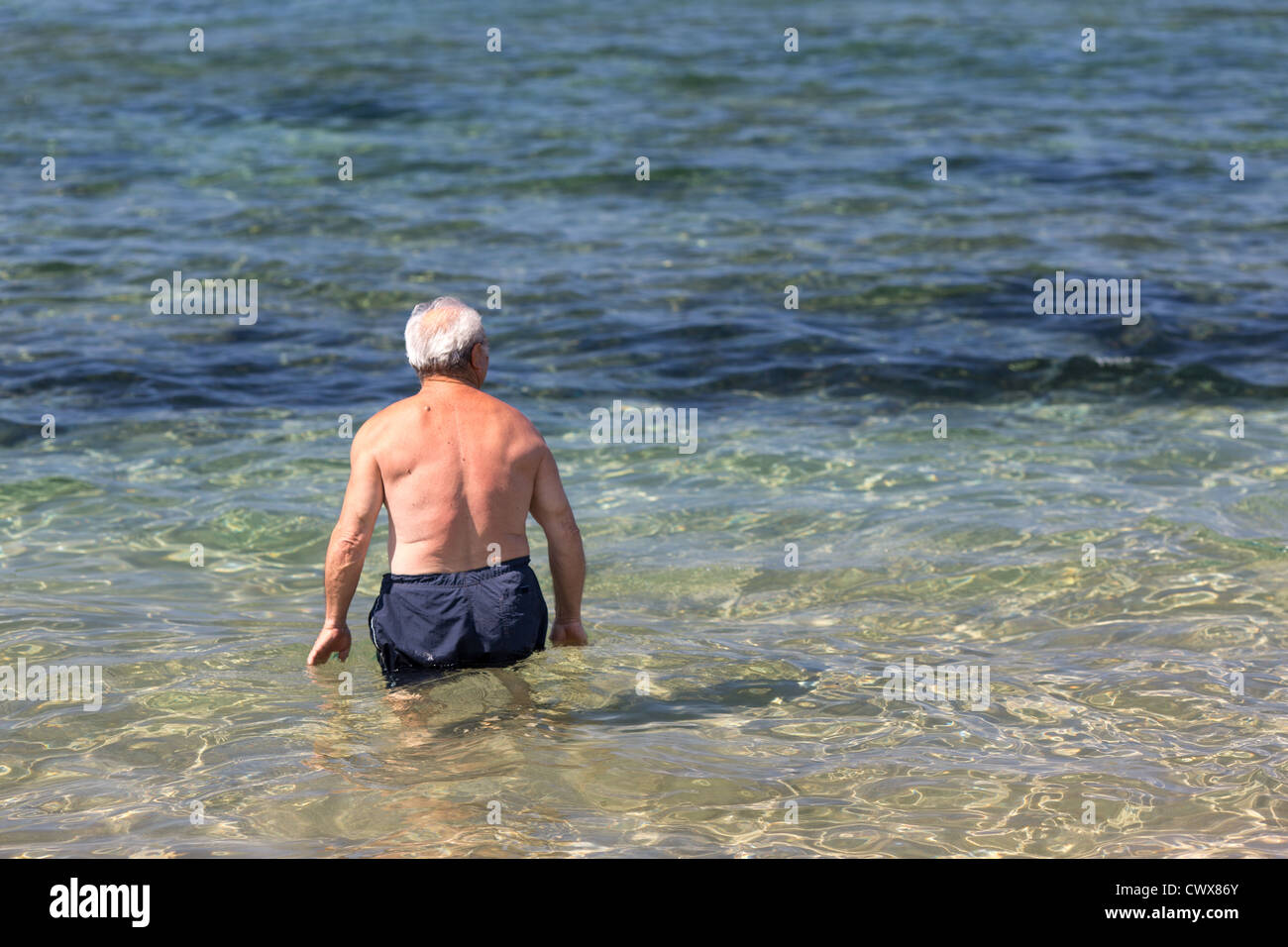 Un touriste âgé prend un bain dans la mer à Agios Georgios, Corfou, îles Ioniennes, Grèce. Banque D'Images
