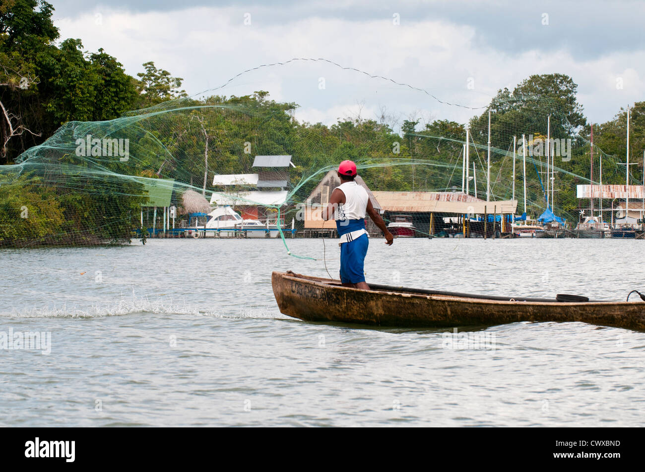 Le Garifuna pêcheur en pirogue voile casting filet de pêche sur le lac d'Izabal, Lago de Izabal, Guatemala. Banque D'Images