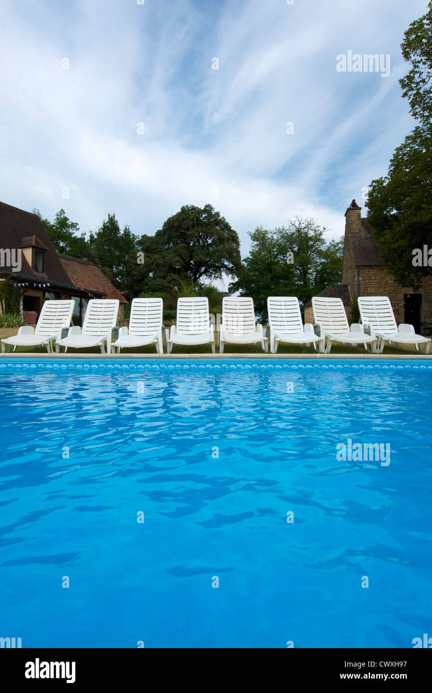 Une rangée de chaises blanches chaise longue au bord d'une piscine en  Dordogne, Aquitaine, France avec un ciel bleu fond de nuage cirrus Photo  Stock - Alamy