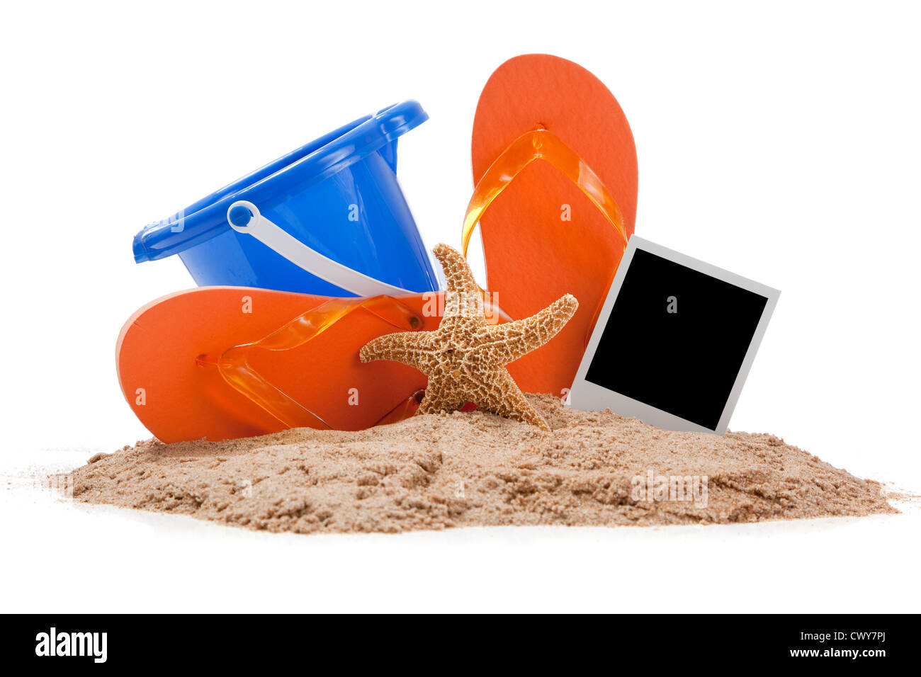 Une paire de tongs orange, bleu seau, étoiles et un polaroid sur le sable Banque D'Images