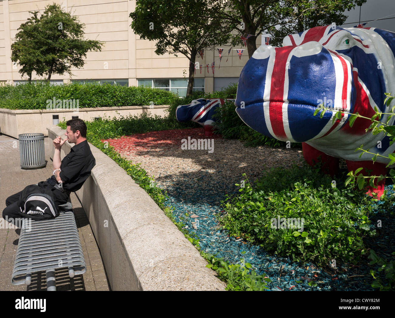 Un homme bénéficiant d'une cigarette dans du plastique d'hippopotames au centre commercial de Cribbs Causeway, peint par l'artiste Benjamin Jones. Banque D'Images