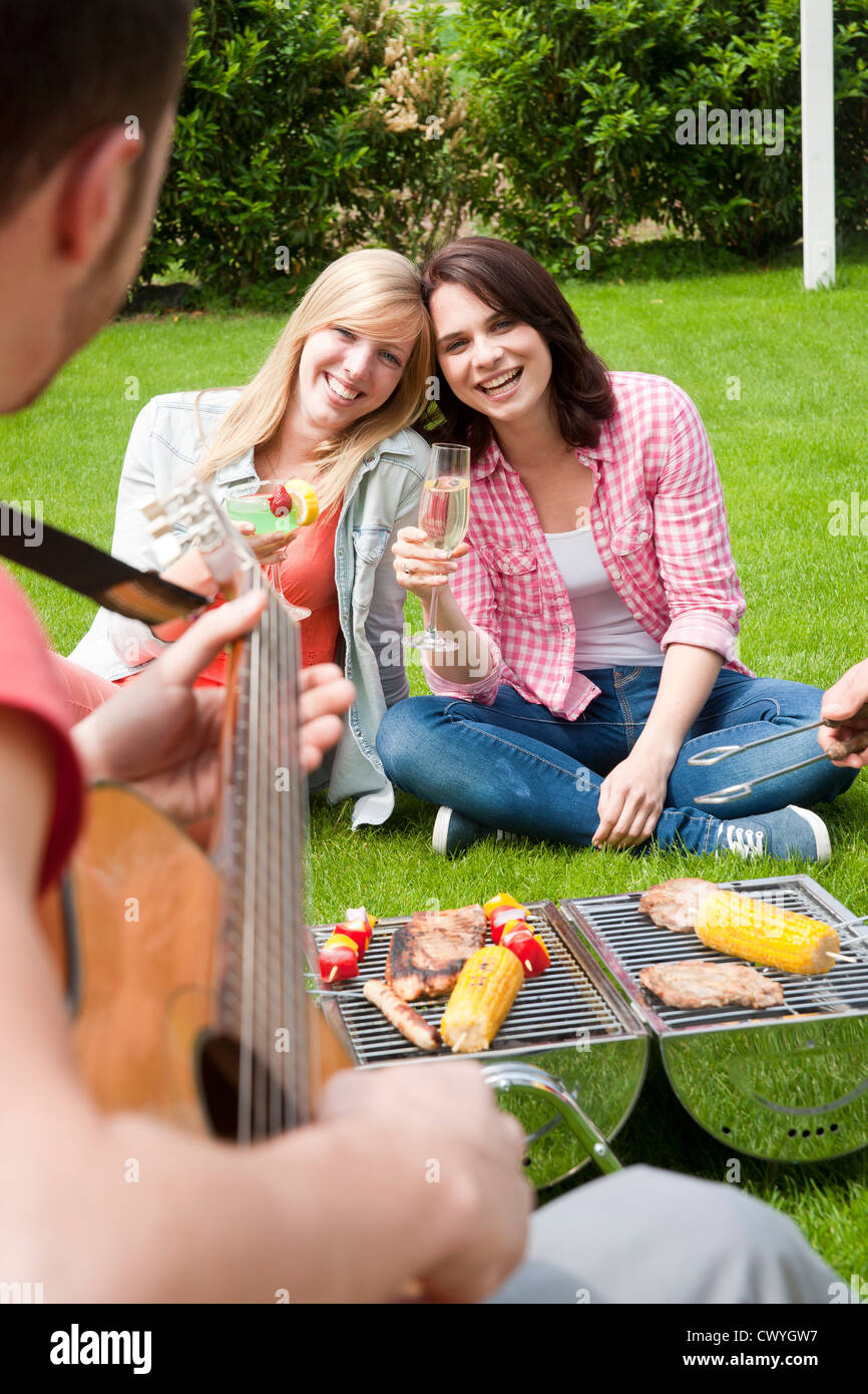 Les amis d'avoir un barbecue sur la pelouse Banque D'Images