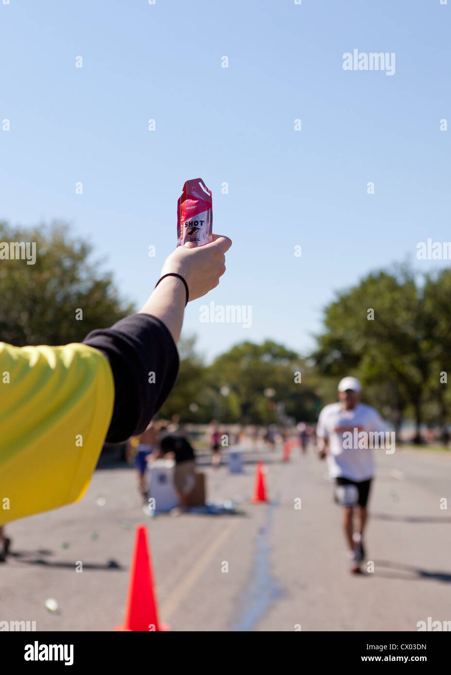 Un marathon offre de bénévolat energy gel à runner - USA Banque D'Images