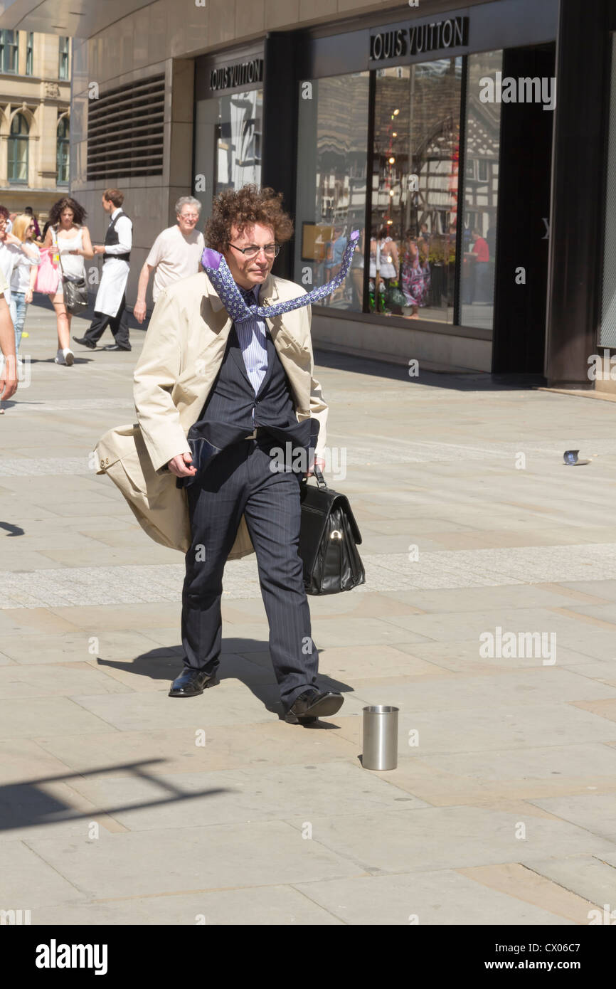 La statue ou statue vivante mime de rue se faisant passer pour un homme d'affaires pressé, windswept à Manchester. Banque D'Images