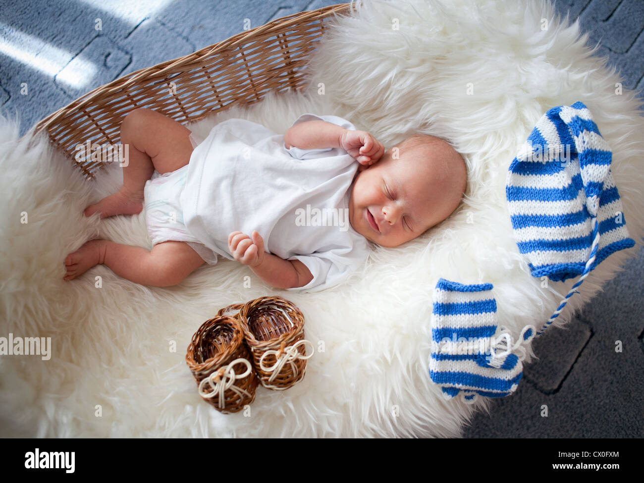 Sleeping newborn baby in wicker basket allongé sur la peau de mouton Banque D'Images