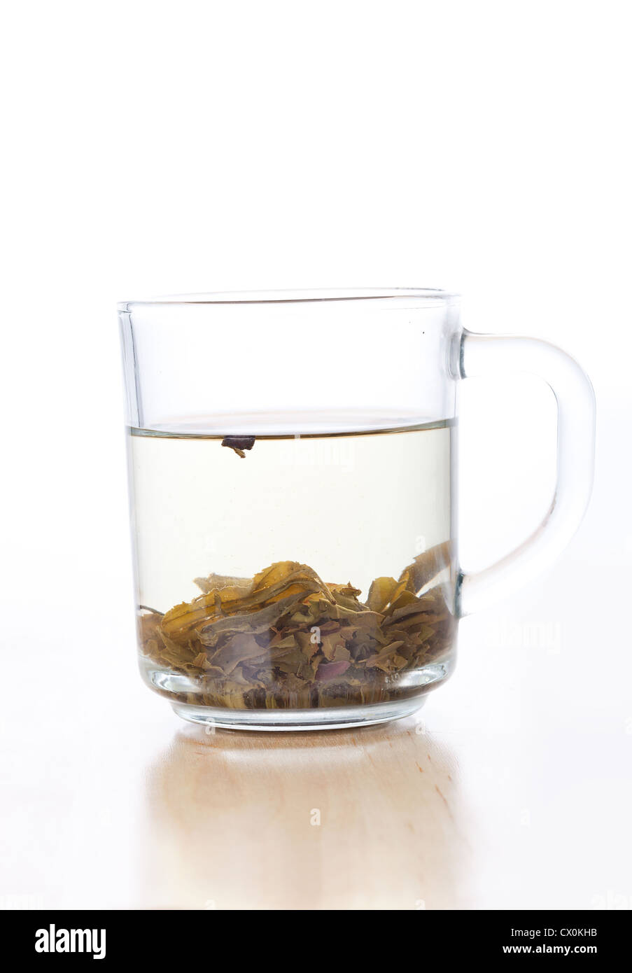 Tasse en verre de thé vert avec des feuilles, gros plan sur fond blanc Banque D'Images
