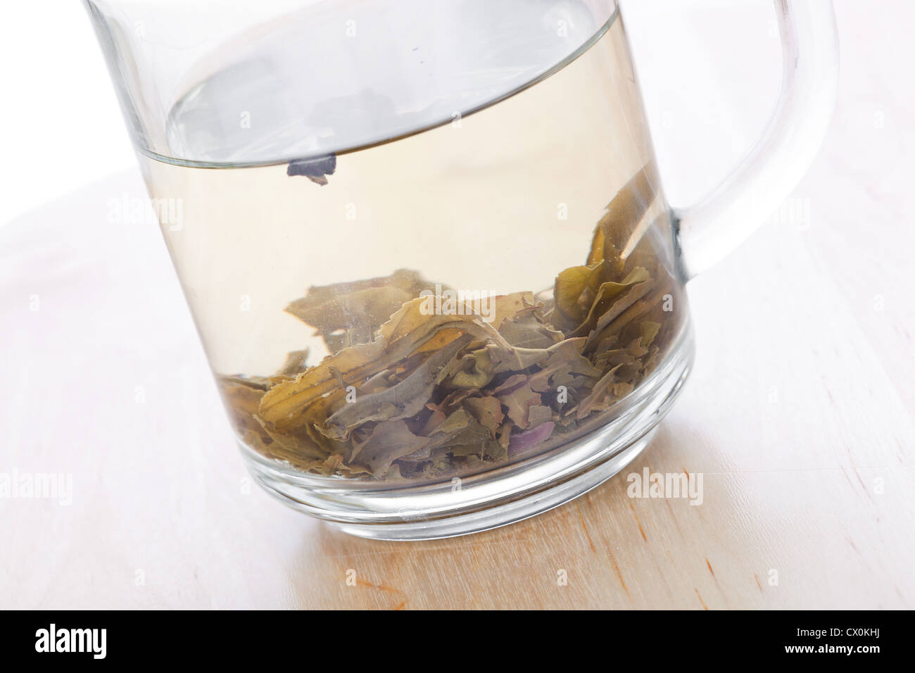 Tasse en verre de thé vert avec des feuilles, closeup on wooden table Banque D'Images